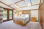Primary bedroom has soaring ceilings and French doors to the deck
